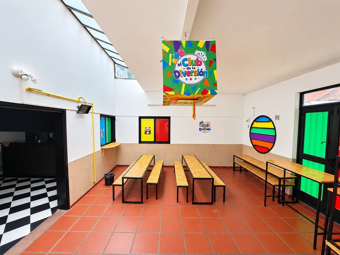 Comedor de los chicos con mesas largas, bancos de madera y piñata