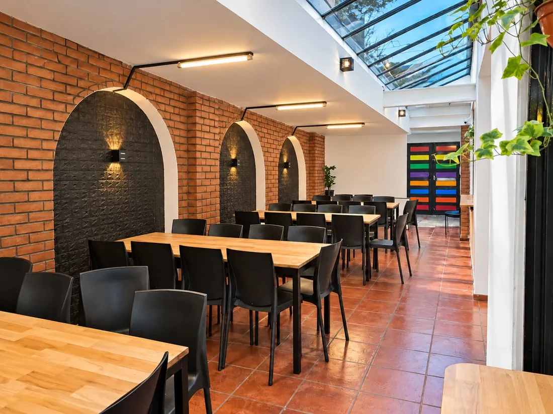 Comedor con paredes de ladrillo, arcos iluminados, mesas de madera y techo vidriado