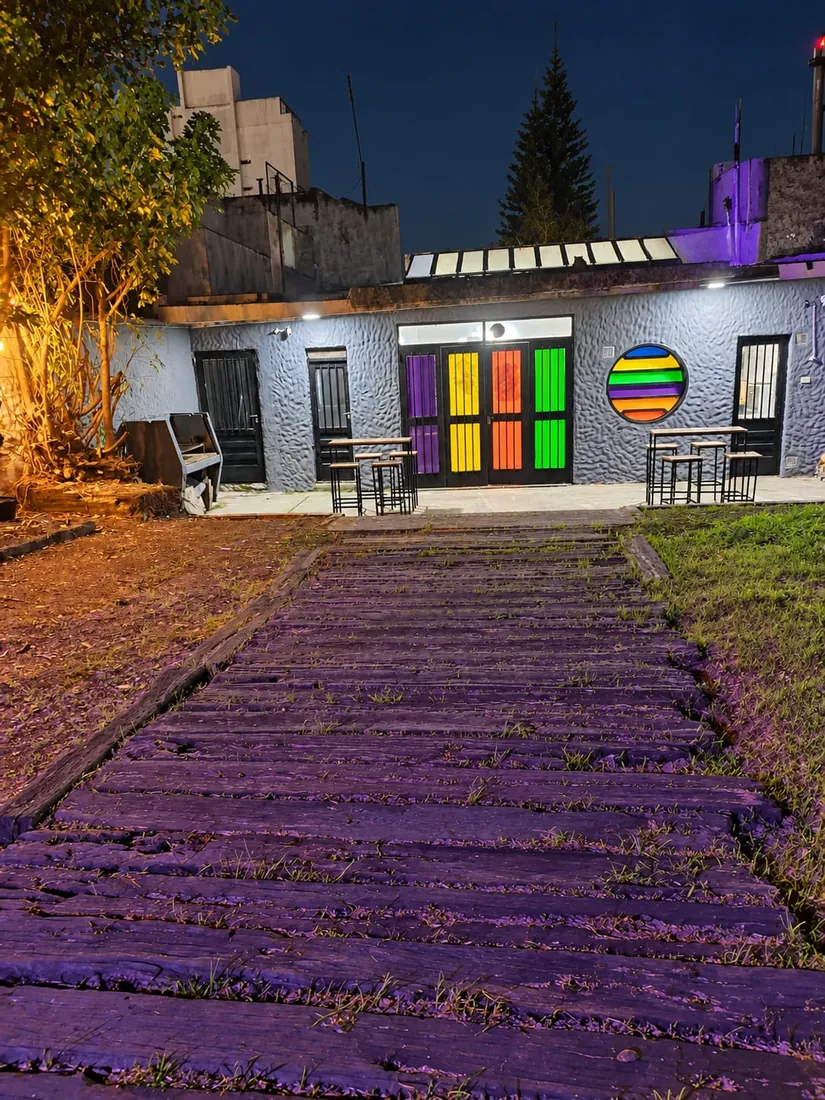 Patio de noche con luces cálidas y el frente de colores del club
